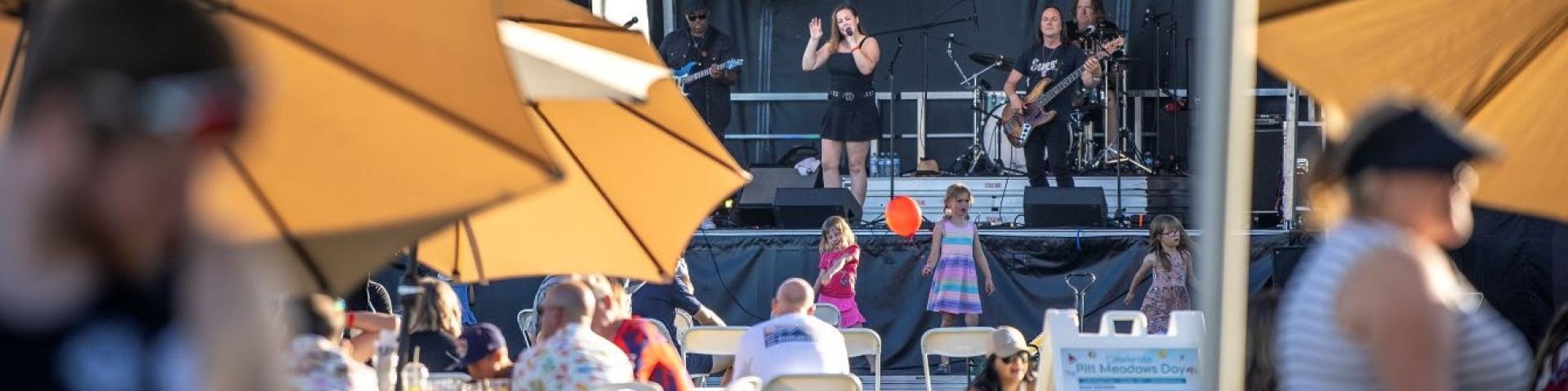 stage with a band performing and yellow umbrellas and people in the fore ground