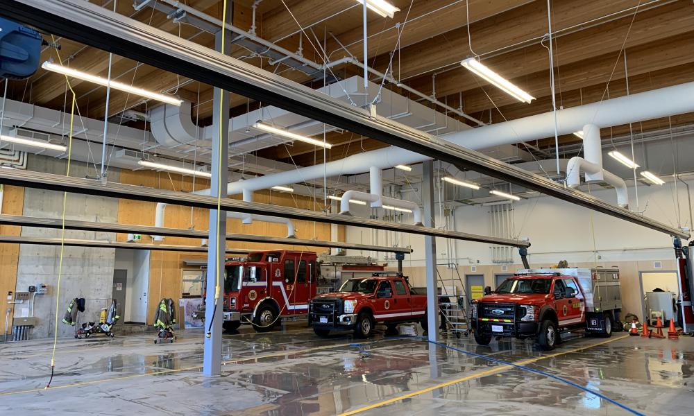 View of inside of fire hall aparatus bay with three fire trucks inside