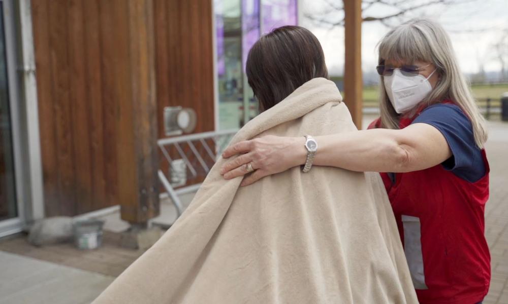 ESS volunteer places blanket over a person's shoulders.