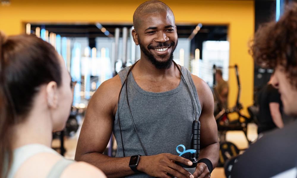gym setting with a man in a grey tank top smiling