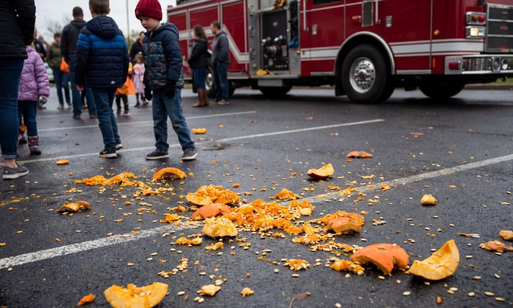 smashed pumpkin splattered on ground with a firetruck in the background