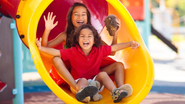 two kids playing on a playground slide